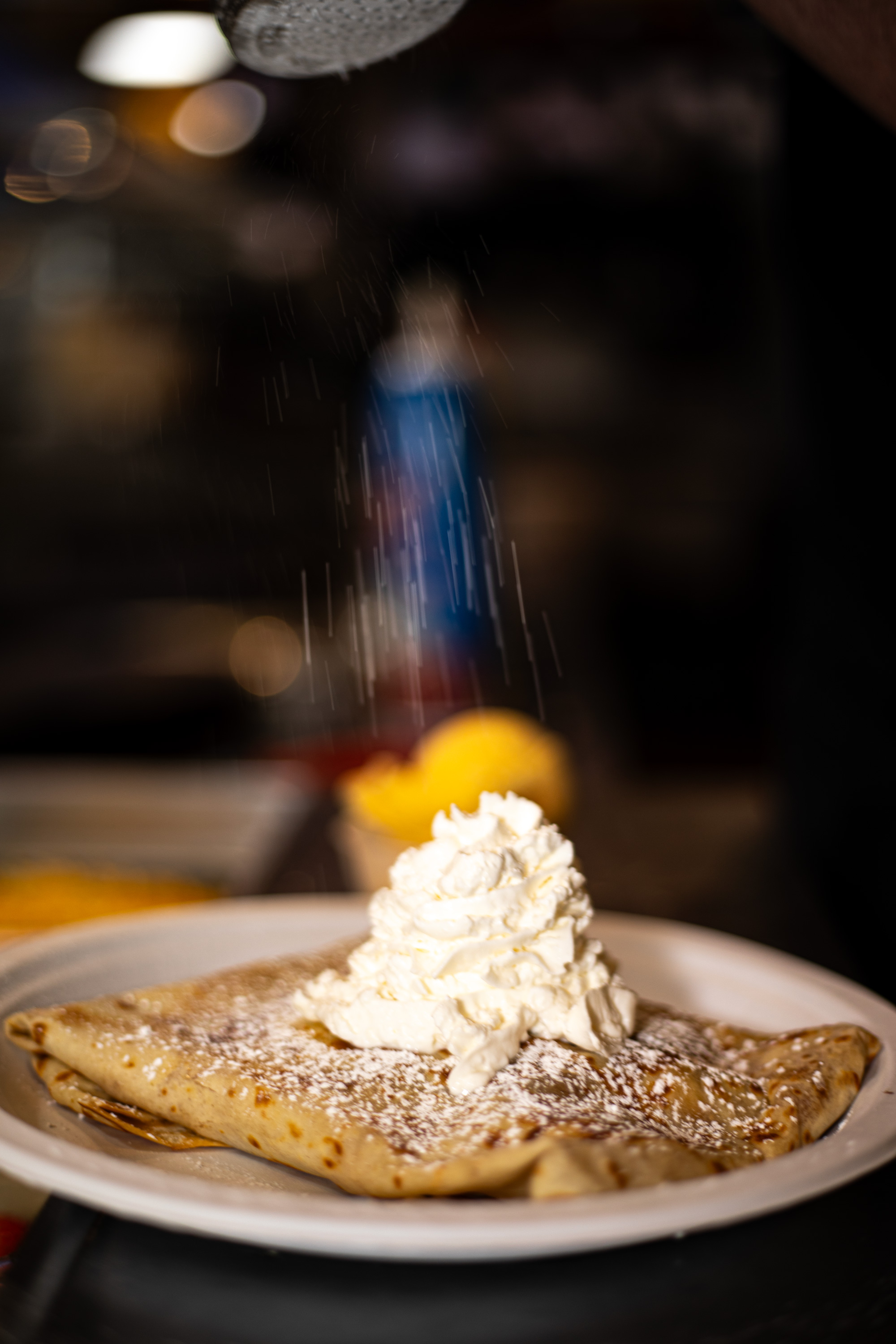 Crêpe being finished with whipped cream